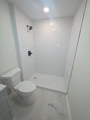 A bathroom with a toilet, a shower area, and a tiled floor.