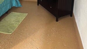 Ein Schlafzimmer mit einem Bett, einem Schminktisch, einem kleinen Tisch und einem Deckenventilator.