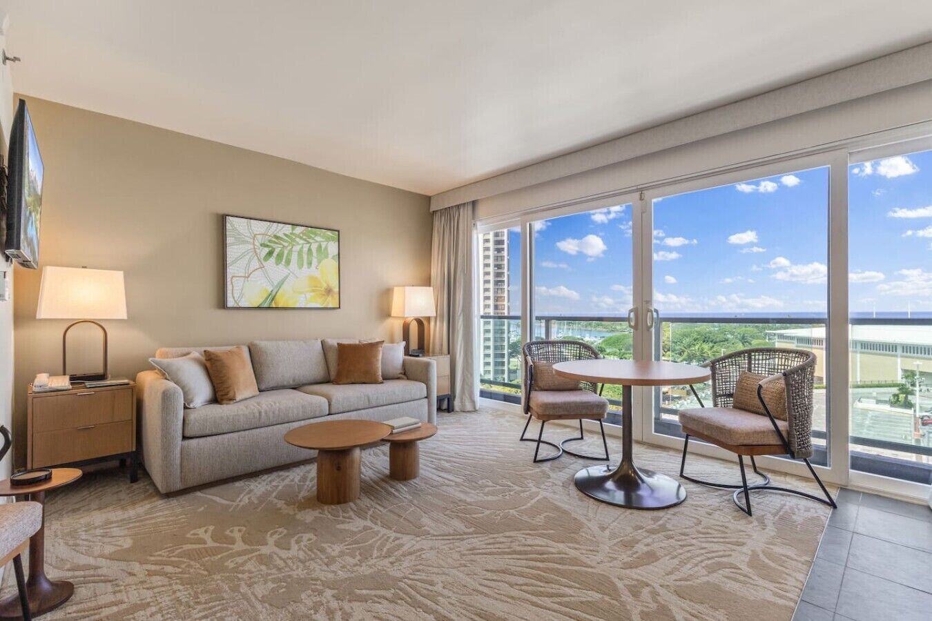 Une chambre d’hôtel avec un canapé, deux tables d’appoint, une table basse, une chaise et un balcon avec vue.