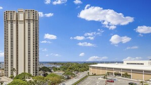 A high-rise building with a clear view of the ocean and a parking lot in the foreground. - Ala Moana 1 Bedroom · Ocean Views, Beach, Mall (Honolulu)