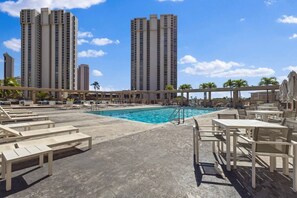 A rooftop pool area with lounge chairs and tables, surrounded by tall buildings. - Ala Moana 1 Bedroom · Ocean Views, Beach, Mall (Honolulu)