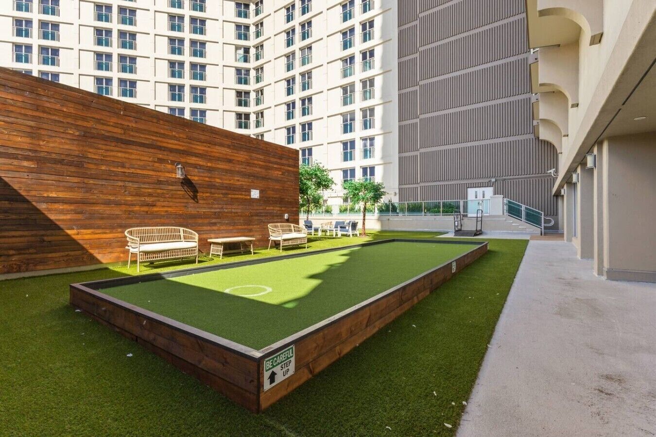 Un espace extérieur comprenant une table de billard, des chaises et un mur en bois.