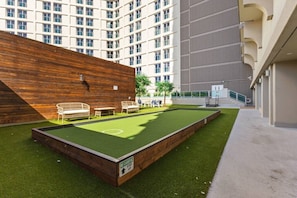 Un espace extérieur comprenant une table de billard, des chaises et un mur en bois.
