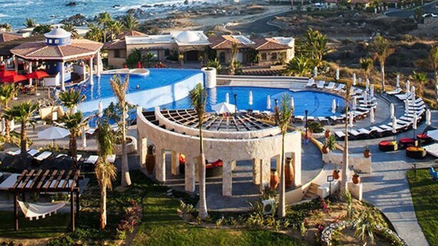Un resort con una grande piscina, aree relax e vista sull'oceano.