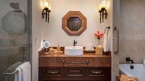 Un bagno con uno specchio rotondo, due luci a parete, un portascopevoli, un lavandino e una vasca da bagno.