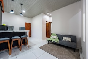 Eine moderne Küche mit Barbereich, einem grauen Sofa und einer Holztür.
