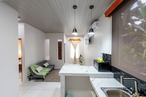 Un espace de vie moderne comprenant un coin cuisine, un canapé, une table à manger et un téléviseur fixé au mur.