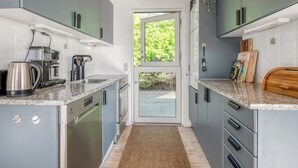 Une cuisine moderne avec des meubles gris, une machine à café et une planche à découper en bois.