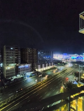 A nighttime cityscape with modern buildings, a multi-lane road, and a bridge with blue lighting. - MOA STAYCATION (Pasay City)