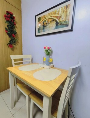A dining table with two chairs, a vase with flowers, and a framed picture on the wall. - MOA STAYCATION (Pasay City)