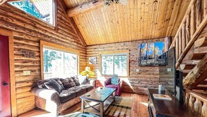 A log cabin interior with a sofa, coffee table, and a TV. - North Star Cabin in Whitefish, near Glacier (Whitefish)