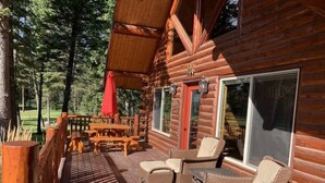A log cabin with a covered porch, outdoor seating, and large windows. - North Star Cabin in Whitefish, near Glacier (Whitefish)