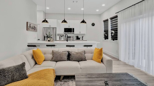 Ein modernes Wohnzimmer mit Sofa, Couchtisch und einer Küche im Hintergrund.