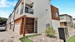 Ein modernes Wohnhaus mit zwei Etagen, einer Garage, einem Balkon und einem kleinen Garten.