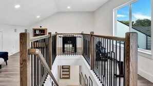 Ein geräumiger Innenraum mit hoher Decke, einer Treppe mit Holzwerteln und einem großen Fenster mit Blick ins Freie.