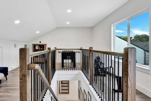 Ein geräumiger Innenraum mit hoher Decke, einer Treppe mit Holzwerteln und einem großen Fenster mit Blick ins Freie.
