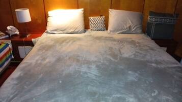 Una habitación de hotel con una cama, una lámpara, un teléfono y una manta a rayas.