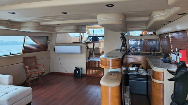 A compact kitchen with a wooden bar, a seating area with a cushioned chair, and a small dining table. - Enjoyable 4-bedroom boat with AC in vibrant Miami Beach (Miami Beach)