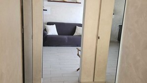 Un passadís que condueix a un saló amb un sofà i una estantària amb objectes decoratius.
