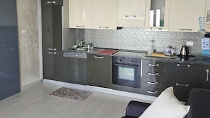 Una cuina moderna amb armaris foscos, forn encastrat i taulell equipat amb diversos electrodomèstics.