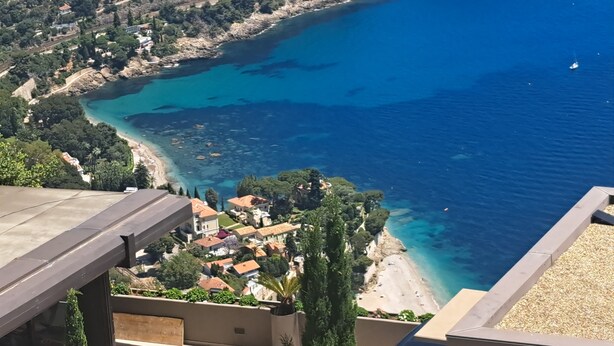 Vista costanera amb edificis, una platja i aigües blaves i transparents.