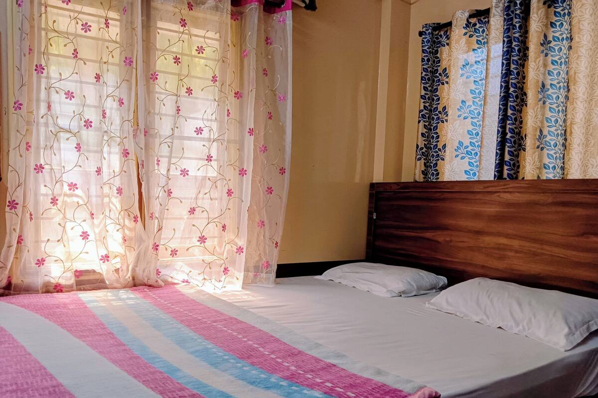 A bed with white bedding, a wooden headboard, and a colorful striped blanket.