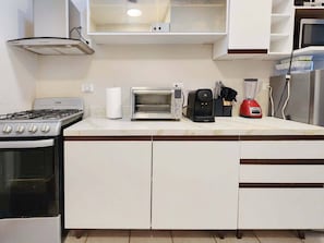 Eine Küche mit Herd, Backofen, Mikrowelle, Toaster, Kaffeemaschine und Mixer.
