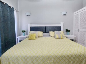 Ein ordentlich eingerichtetes Schlafzimmer mit Bett, Nachttischen, einem Kleiderschrank und einem Vorhang.