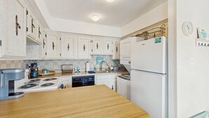 A kitchen with white cabinets, a wooden countertop, a stove, a dishwasher, and a refrigerator. - Lee Ko 19 (Ocean City)