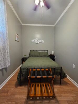 A bedroom with a bed, a ceiling fan, a wall-mounted light fixture, and a small bedside table. - Cozy home away from home (Matthews)