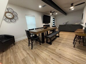 A dining area with a wooden table, black chairs, a bench, and a TV mounted on the wall. - Charming A-Frame Cabin:Water View & Large Yard,13 miles to Universal Kids Resort (Oak Point)