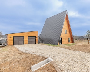 A modern building with a sloped roof, a garage, and a gravel driveway.