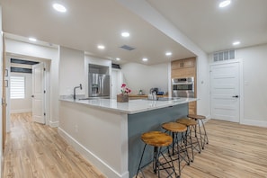 A modern kitchen with a large island, bar stools, and built-in appliances.