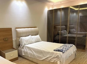 A bedroom with a bed, bedside table, and a wardrobe with mirrored doors. - Pent House Saed (Marsa Matrouh Governorate)