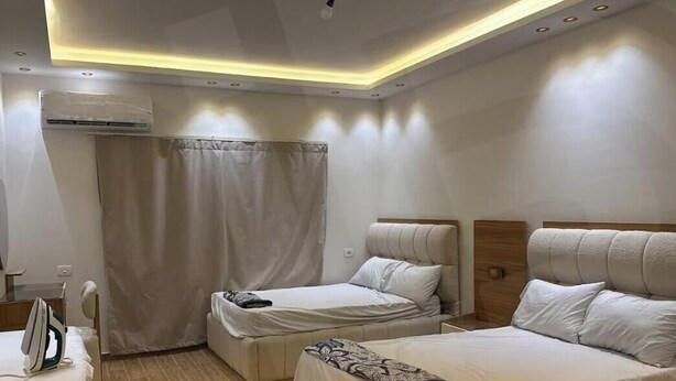 Une chambre d’hôtel avec deux lits, un climatiseur, un luminaire au plafond et un rideau.