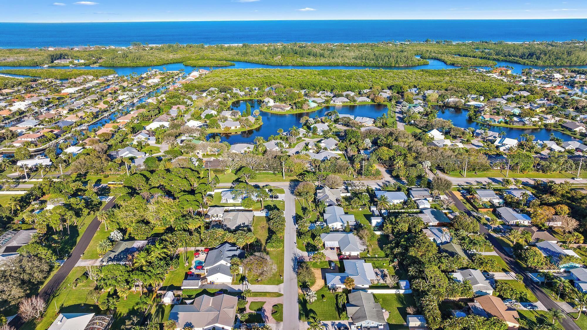 An aerial view of a residential area with houses, roads, and water bodies.