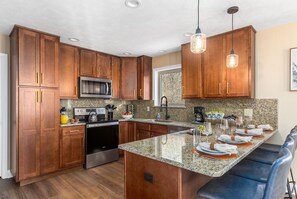 Eine Küche mit Holzausstattung, Edelstahlgeräten, Granit Arbeitsplatten und einer Bar mit Sitzgelegenheiten.