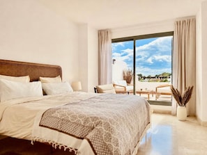 Ein Schlafzimmer mit einem großen Bett, einem Sitzplatz auf dem Balkon und Blick zum Himmel.
