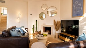 Ein modernes Wohnzimmer mit Kamin, Ledersofas, einem Couchtisch und einem Flachbildfernseher.