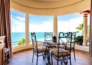 A room with a curved glass wall, a round table with chairs, and a view of the ocean. - Casa Dos Pisos - Combined 2-Unit Beachfront House San Felipe Baja California (San Felipe)