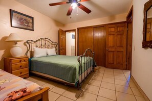 A bedroom with a bed, a nightstand, a lamp, a ceiling fan, and wooden doors. - # El Mirador del Golfo - 5BR Beachfront Rental (San Felipe)