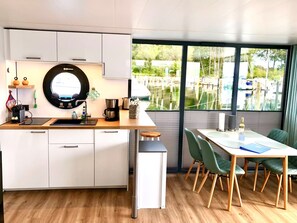 Una cocina moderna con un ventanal redondo, encimera de madera y un comedor con sillas verdes.