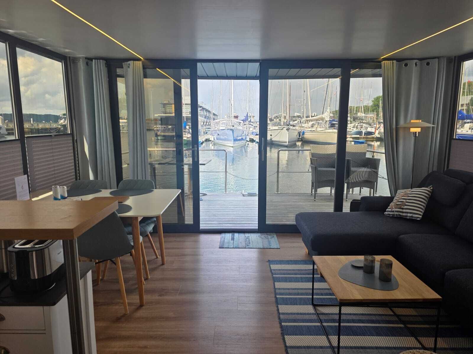 A modern living room with a balcony overlooking a marina.