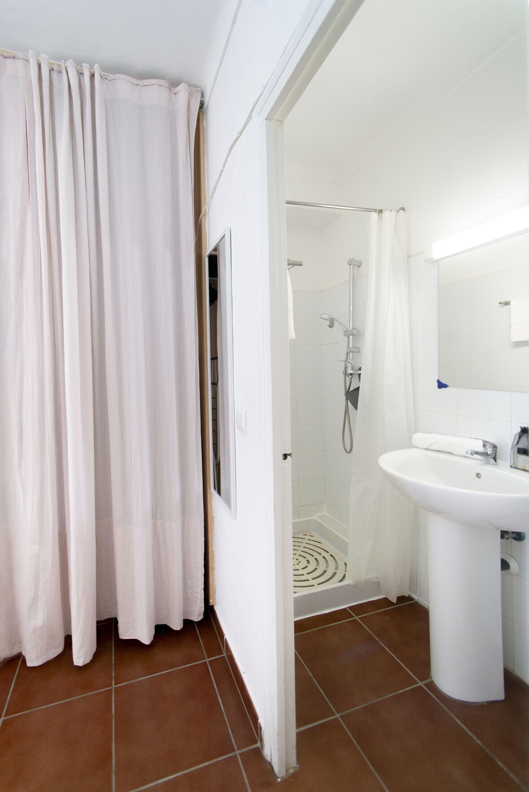 Un baño con ducha, lavamanos y cortina.