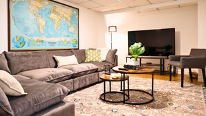 Sala de estar com um grande mapa-múndi, sofá, mesa de centro, televisão e abajur.