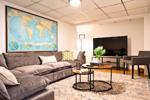 Una sala de estar con un gran mapa mundial, un sofá, una mesa de centro, un televisor y una lámpara.