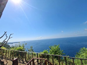A coastal view with a clear sky, a wooden railing, and a distant bridge. - Cozzy Sea Dream Cliff Eco Guest House (Penida Island)
