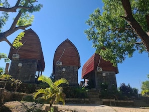 Three stone structures with red roofs, surrounded by greenery and trees. - Cozzy Sea Dream Cliff Eco Guest House (Penida Island)