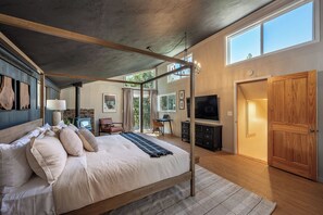 A bedroom with a four-poster bed, a TV, a wooden wardrobe, and a large window. - View Cabin - Mountain Retreat w/ Hot Tub + Sauna (Springville)