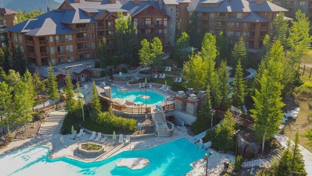 A resort with multiple buildings, a central pool area, and surrounding greenery.